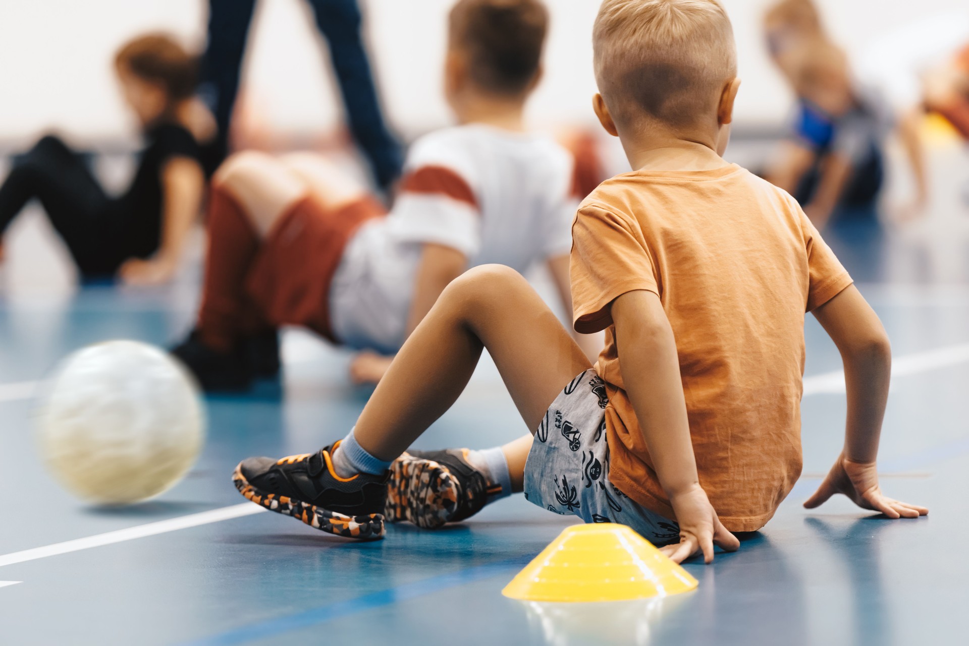 Children in physical education class at school. Group of little boys crawling on the indoor training field. Indoor soccer futsal practice for elementary-age children